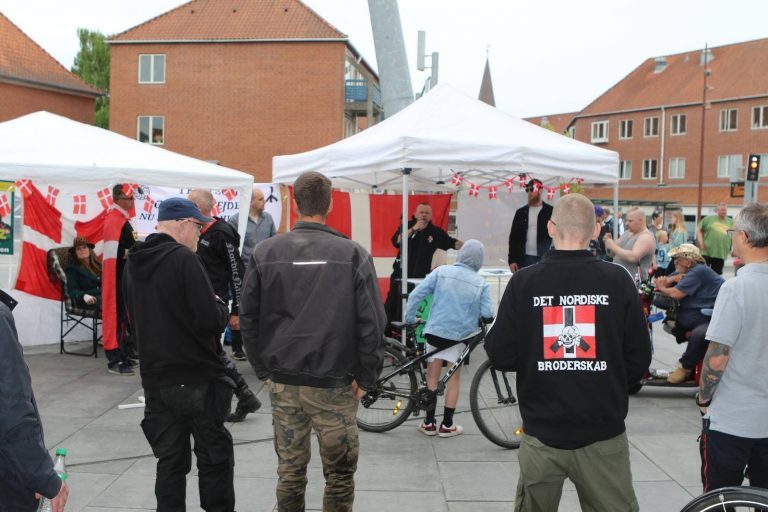 DNBs leder Sandy Steen Kristensen holder her tale ved demonstrationen i Vejle. I forgrunden ses et DNB-medlem i sort trøje med Totenkopf-symbolet. Foto: Redox.