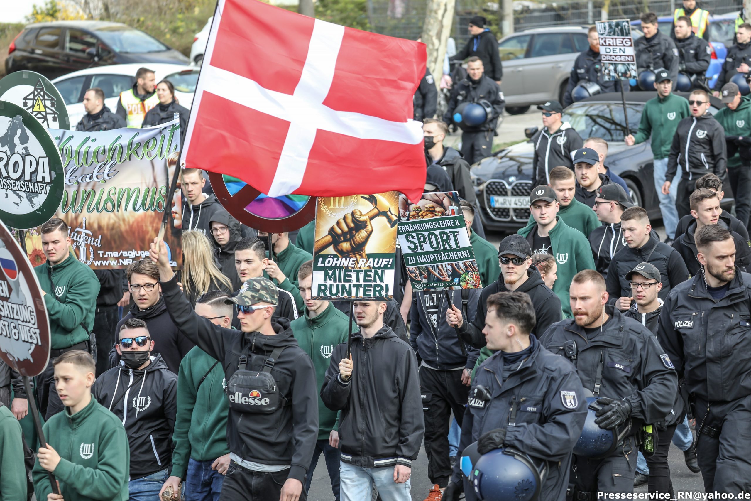 Active Club Denmark til nazimarch i Berlin. Frederik Johan Gustafsson Jensen ses med Dannebrog i hånden. Lidt til højre, med kasket og solbriller, ses hans bror Adam Emil Gustafsson Jensen.