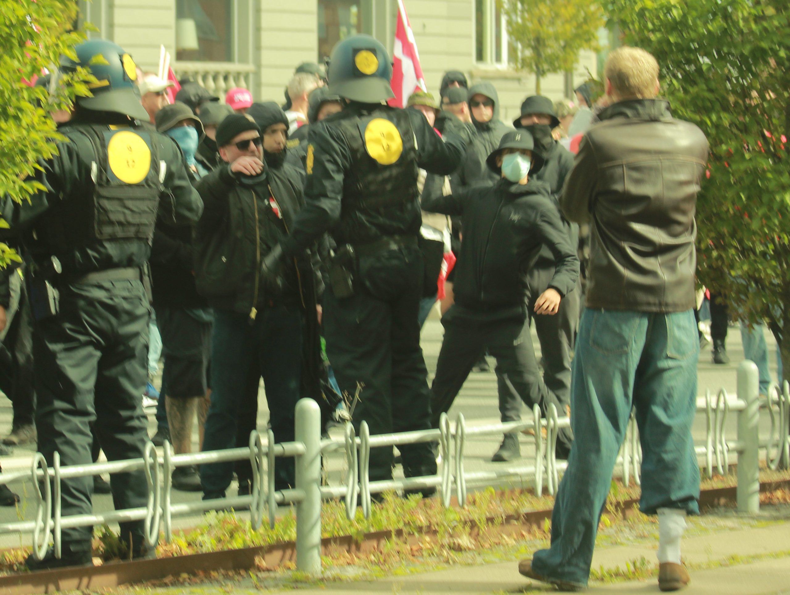 En maskeret hooligan kaster et ukendt objekt mod en person, der står ved siden af remigrationsmarchen.