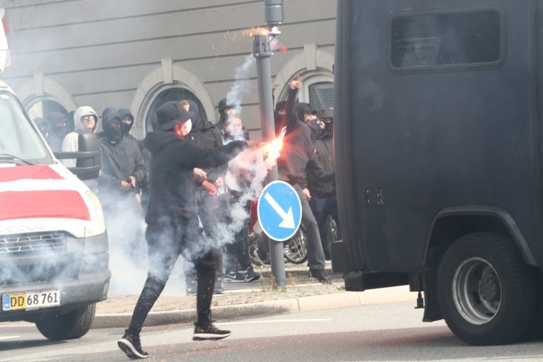 Maskerede hooligans kaster med nødblus mod moddemonstranter.